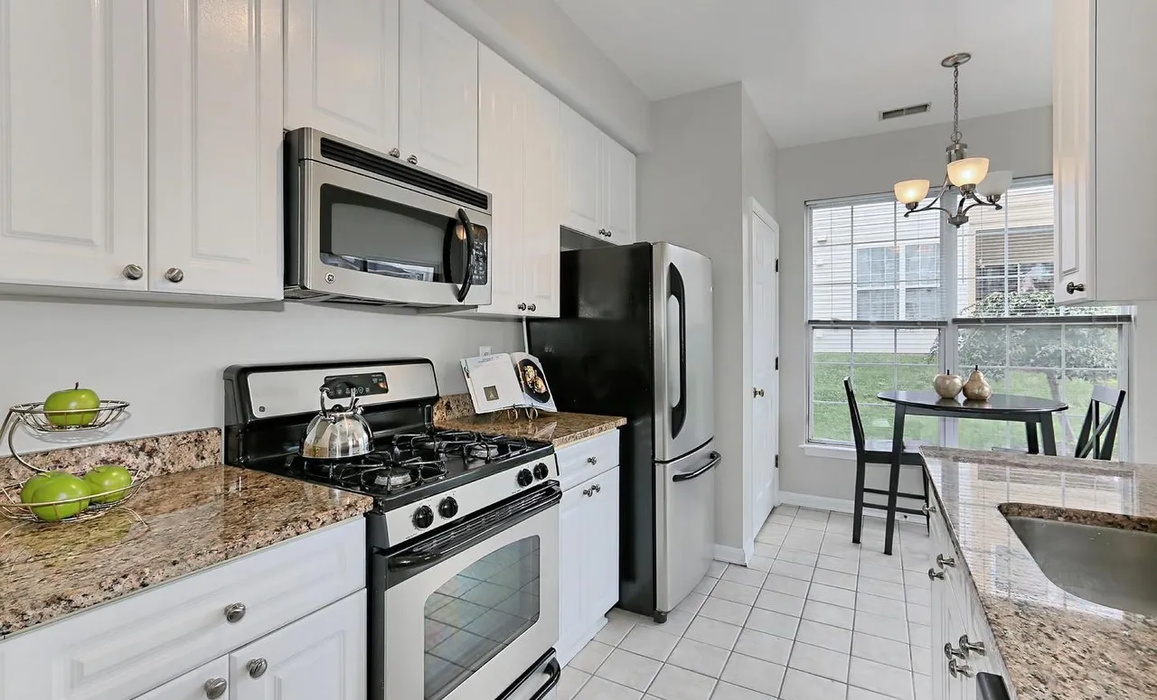 Kitchen with white cabinets, granite counters and stainless appliances.