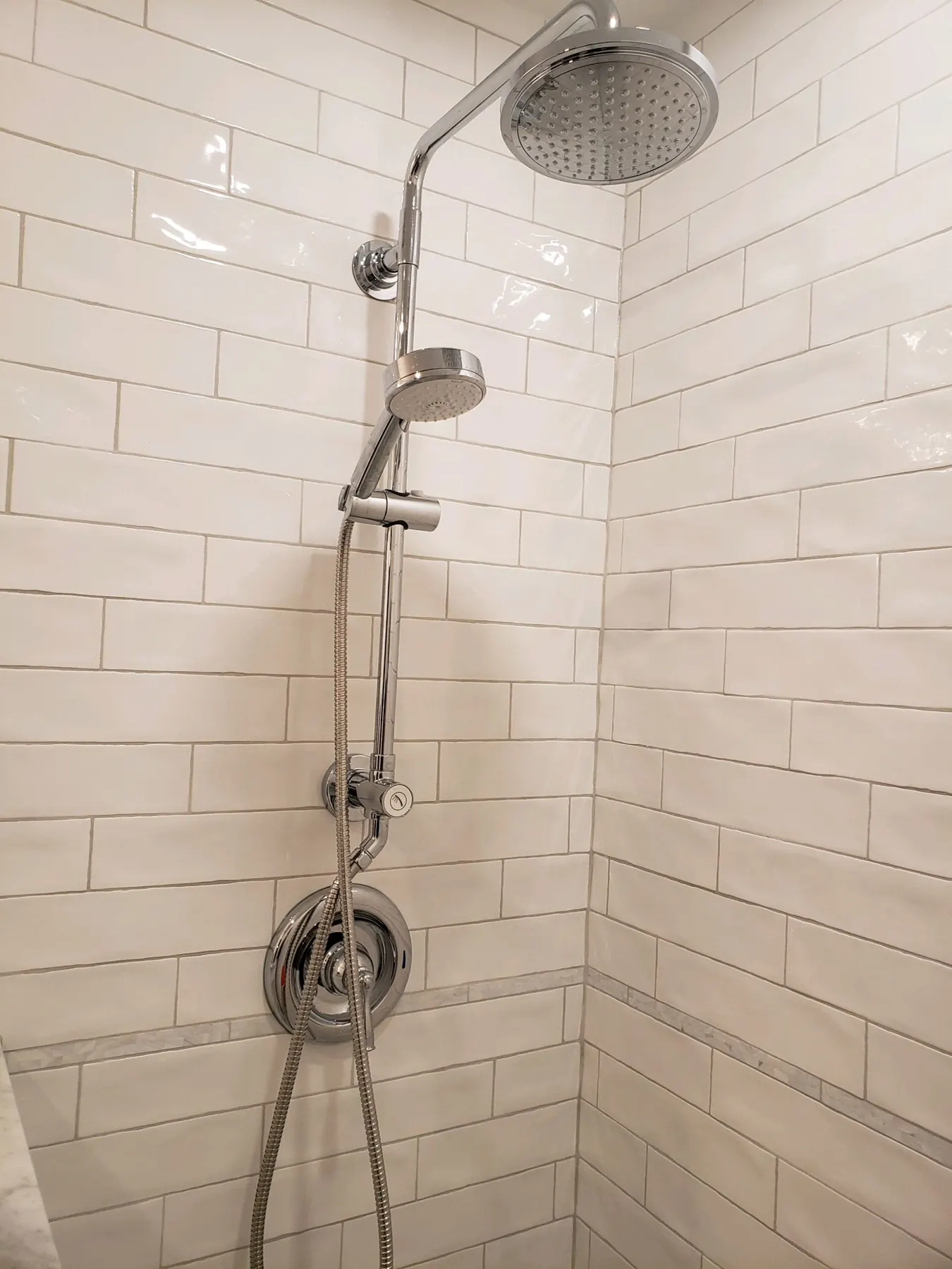 Walk-in shower with white subway tile and a rain shower column.