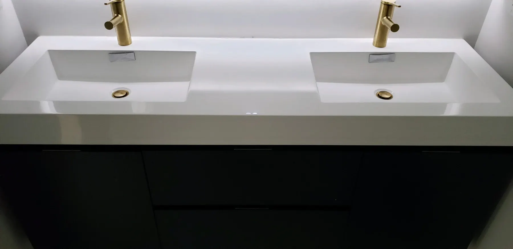 Close-up of brass faucets on a white double vanity.