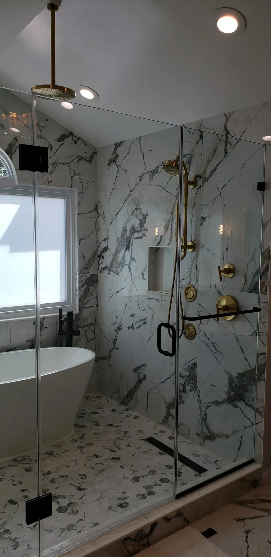 Marble shower with brass and matte black fixtures.