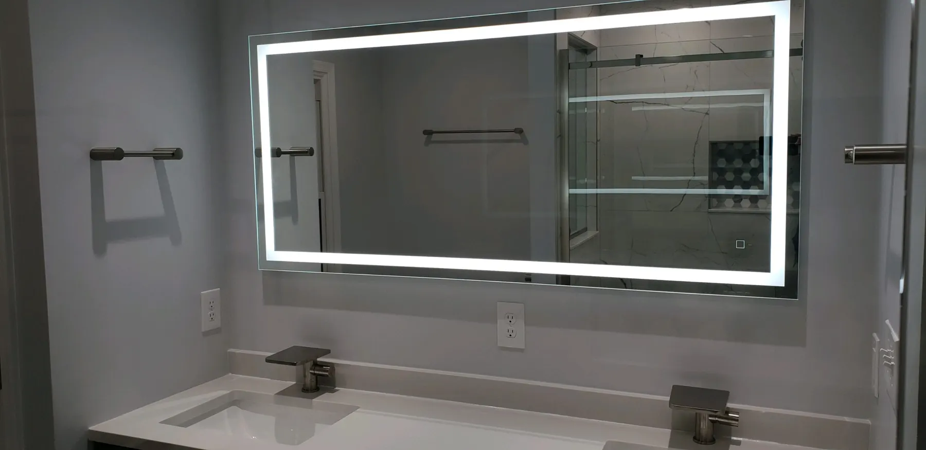 After: modern double vanity with quartz counter and large LED-lit mirror.
